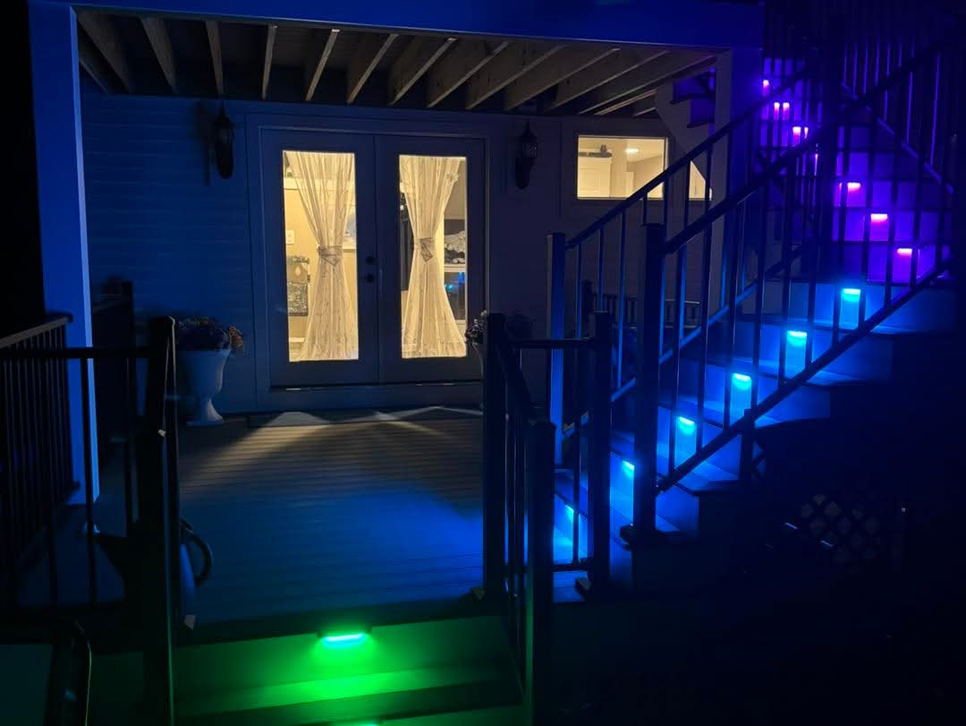 Composite deck stairs lit with blue and green LED riser lighting at night