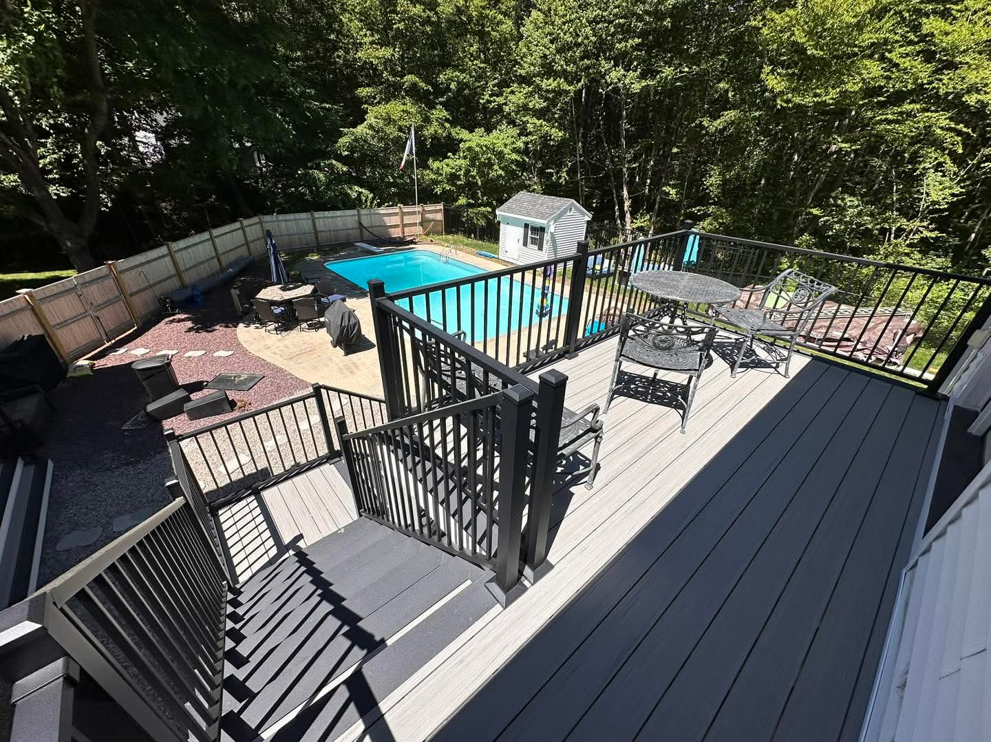 Upper composite deck with black aluminum railing overlooking an in-ground pool