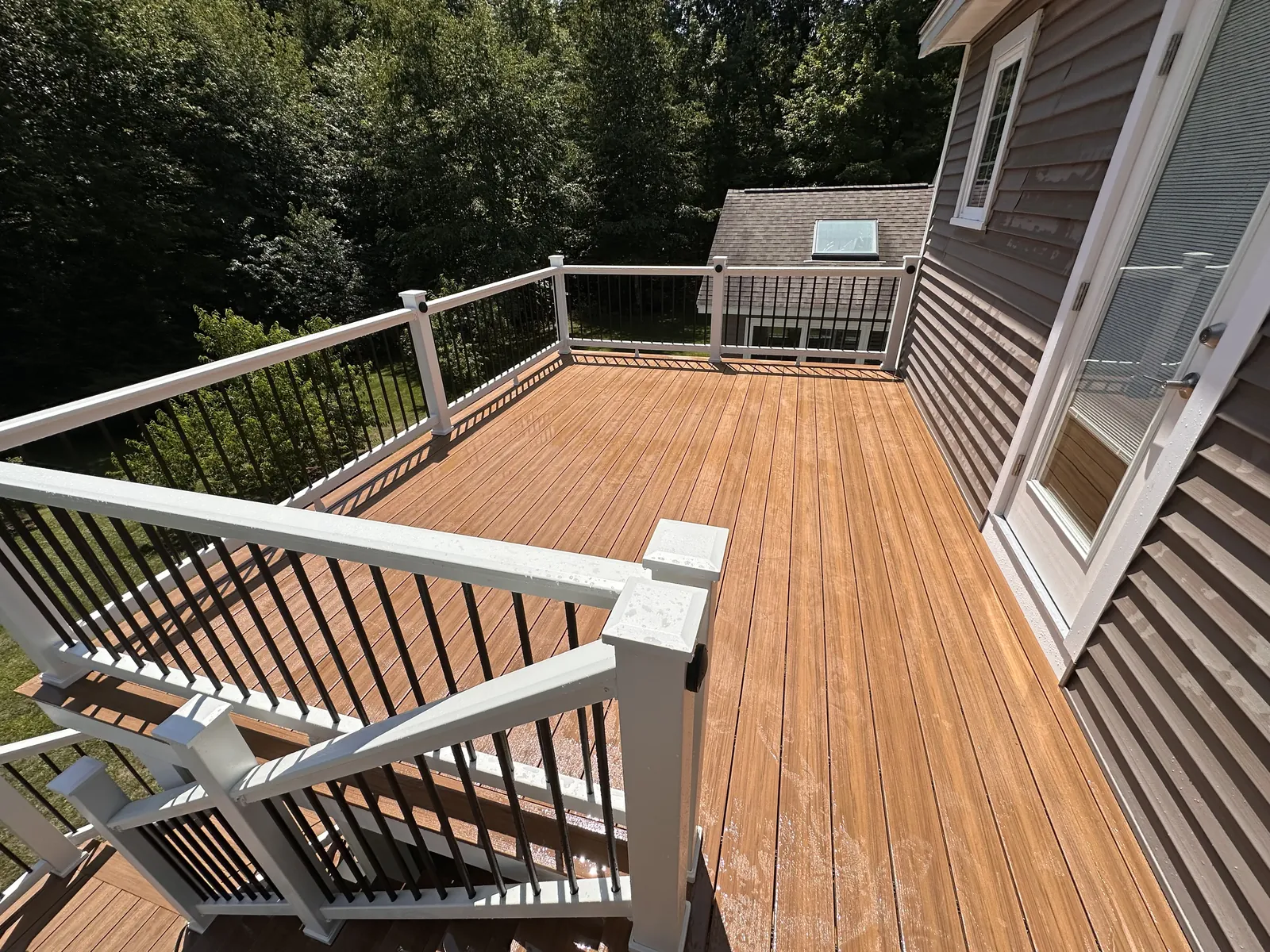 Second-story composite deck surface with white railing and black aluminum balusters in Kingston, NH