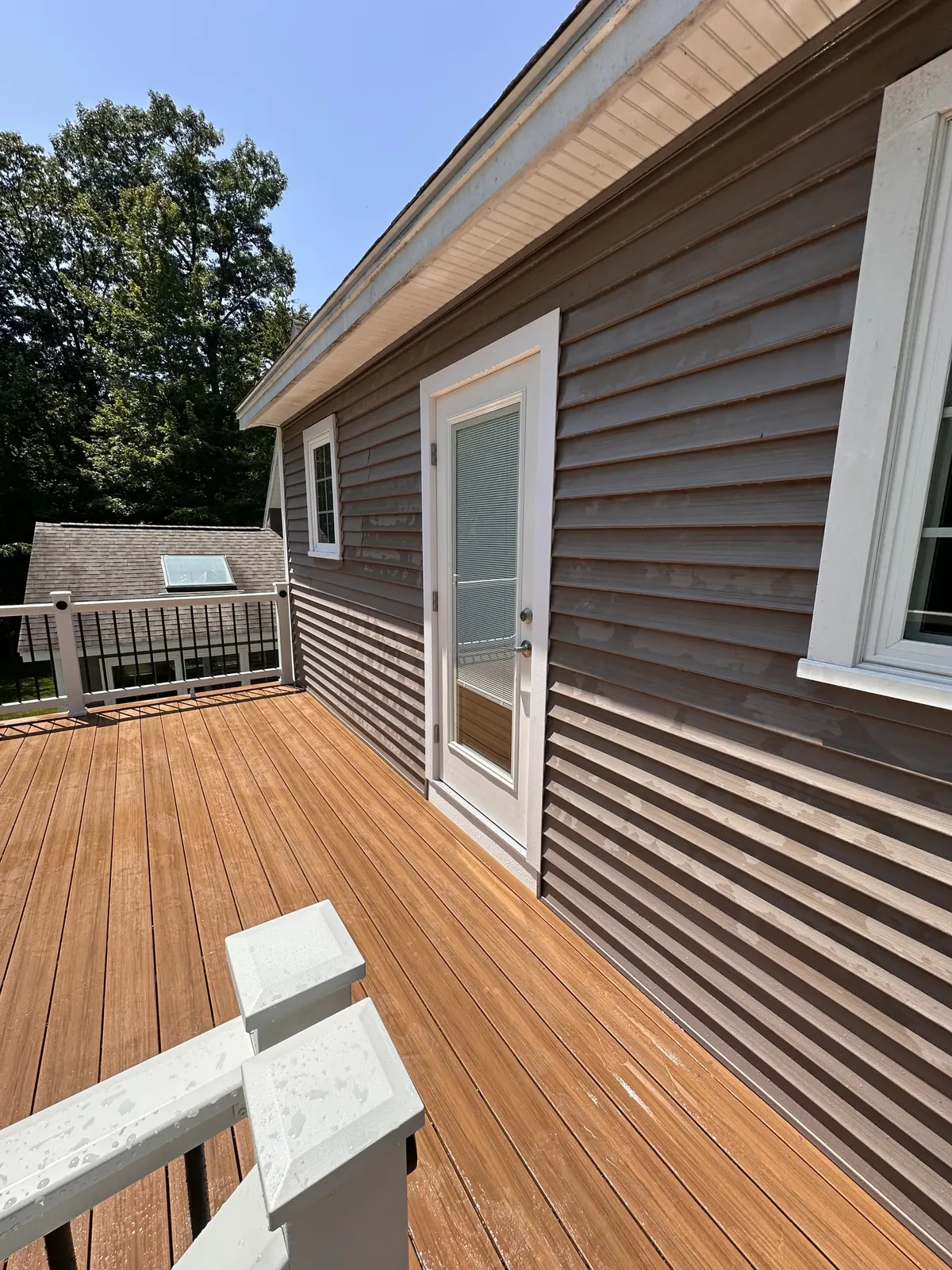 Composite deck boards running to a patio door on an elevated New Hampshire deck