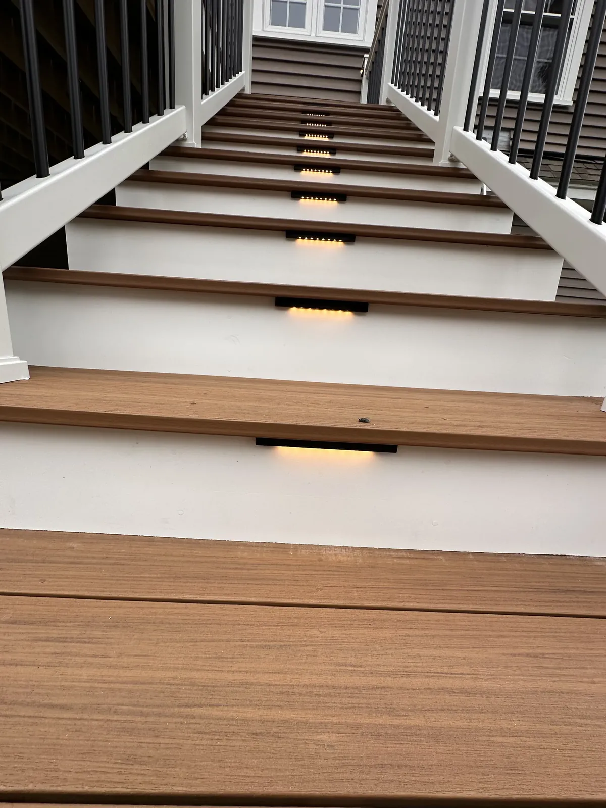 LED stair riser lighting glowing on composite deck steps at dusk in Kingston, NH