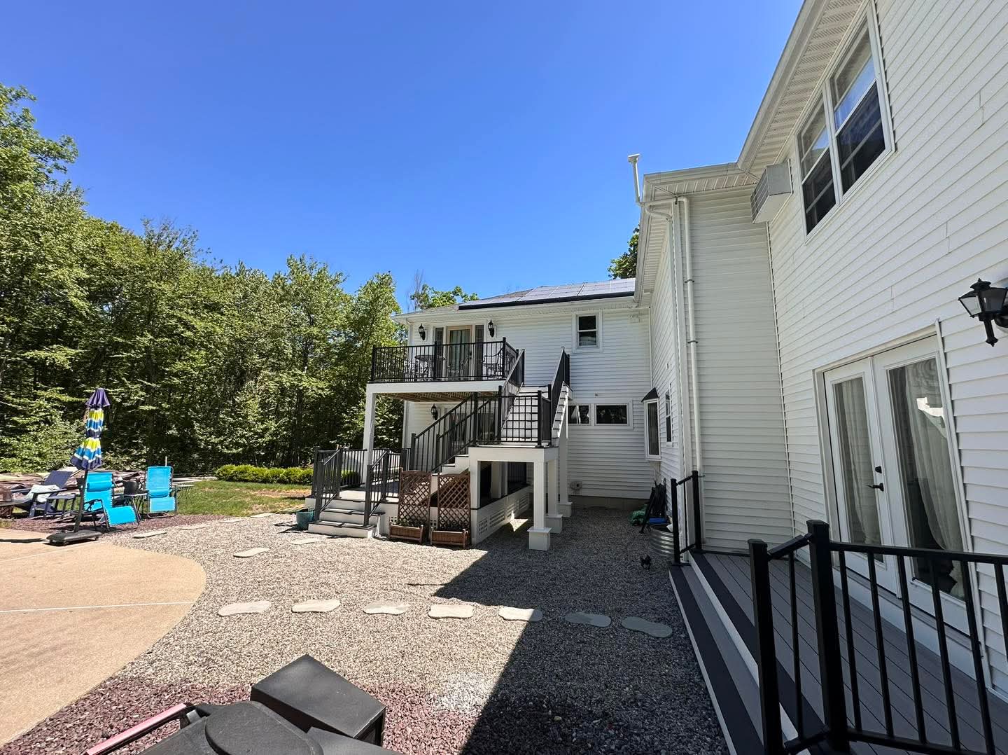 Wide backyard view of a two-level deck, covered porch, and pool patio in New Hampshire