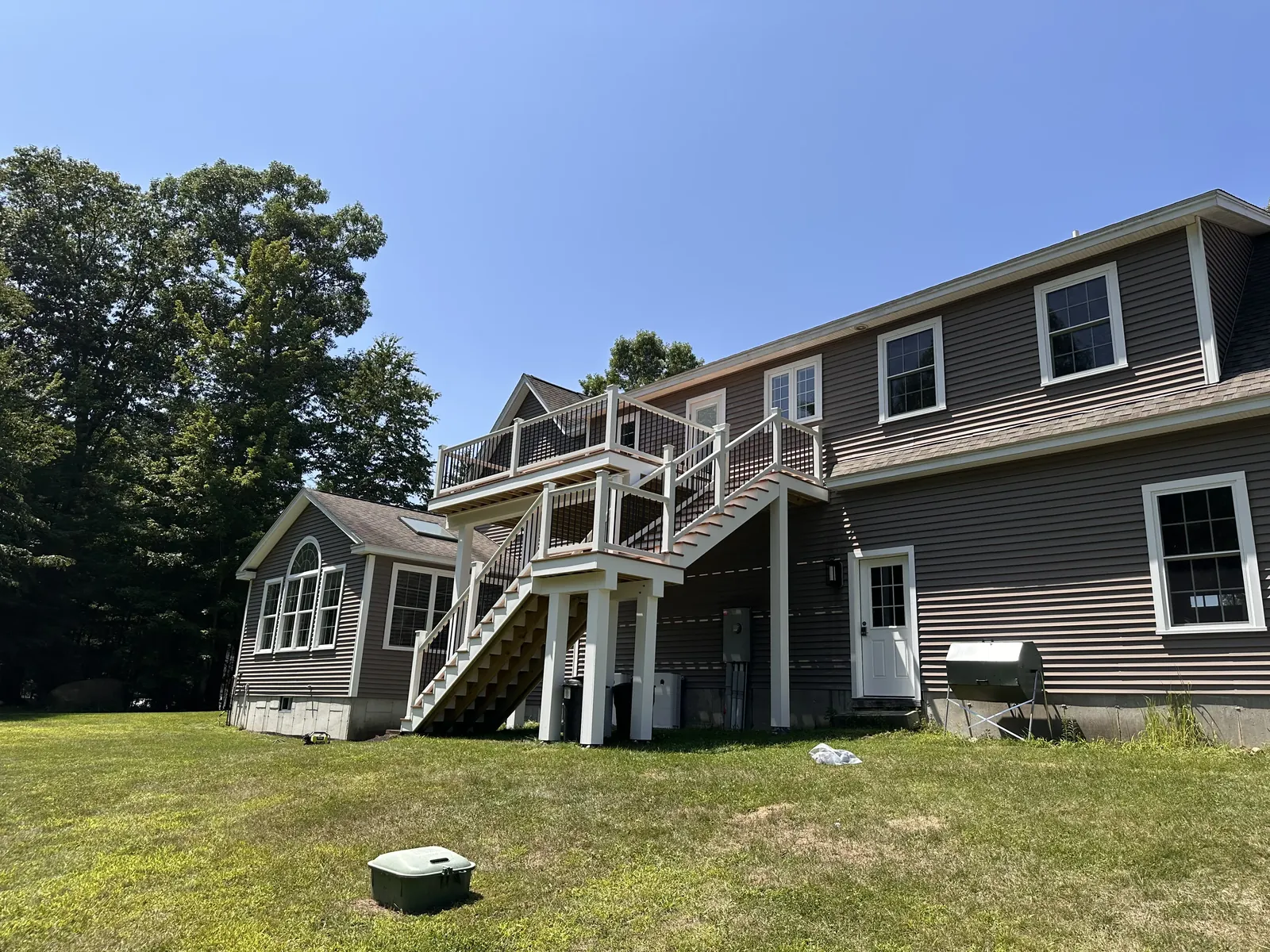 Elevated second-story composite deck with white railing and switchback stairs in Kingston, New Hampshire